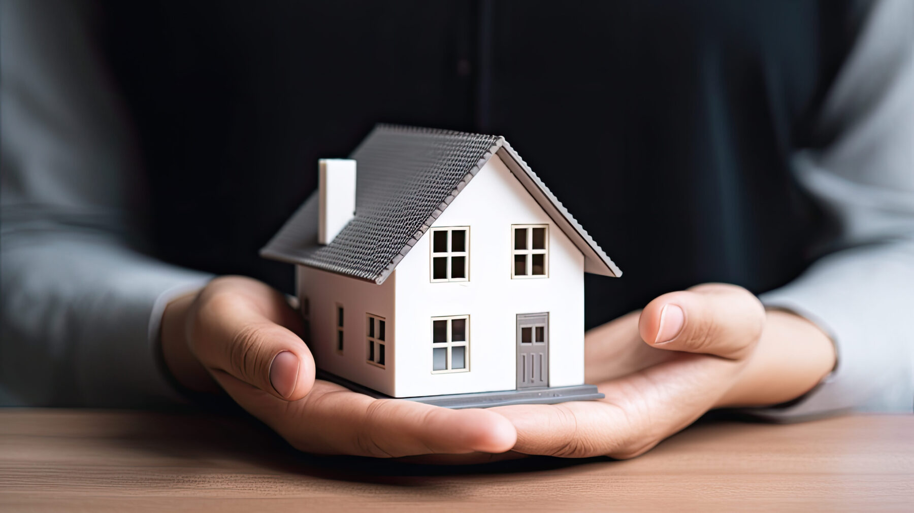 buyers agent commission-a business person holding a house in both hand supporting hands on light brown table scale in economic downturn